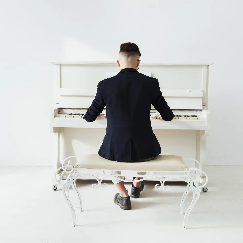 Pianist playing a white upright piano in a bright room